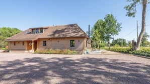 Une maison en bois avec un toit en pente, un porche à l’avant et une allée gravillonnée.