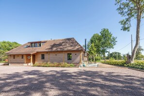 Ein Holzhaus mit geneigtem Dach, einer Veranda und einer Schotterauffahrt.