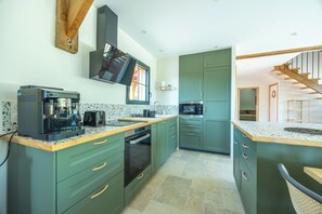 A modern kitchen with green cabinets, a coffee machine, and a microwave. - A charming home on the hills above Trouville (Trouville-sur-Mer)