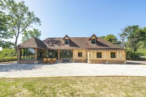 A two-story house with a covered patio, large windows, and a gravel driveway. - A charming home on the hills above Trouville (Trouville-sur-Mer)