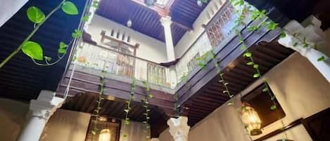 An interior courtyard with a central open space, columns, and hanging plants.