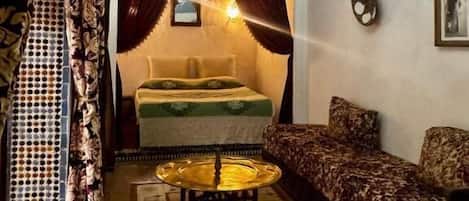 Una habitación con una cama, un sofá, una araña y una alfombra estampada.
