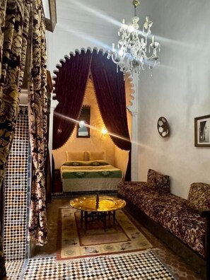 Una habitación con una cama, un sofá, una araña y una alfombra estampada.