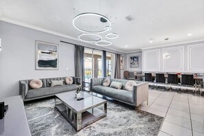 Ein modernes Wohnzimmer mit einem Ecksofa, einem Couchtisch und einem Essbereich mit Stühlen.