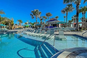 A pool area with lounge chairs and umbrellas, surrounded by palm trees. - Luxury 10BR Windsor Island Villa | 24 | Private Pool | Spa | Game Room |Theater (Davenport)