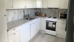 A modern kitchen with white cabinets, a stainless steel sink, a Bosch oven, and a microwave.