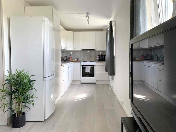 A modern kitchen with white cabinets, a stove, and a microwave.