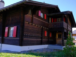 A two-story wooden house with a balcony and red shutters. - Lill Britta 2, mittlere Wohunug Appartement/Fewo, Dusche und Bad, WC, Komfort by Interhome (Arosa)