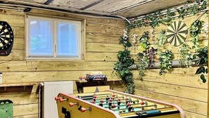 Ett rum med ett fotbollsspel, en darttavla och diverse växter.