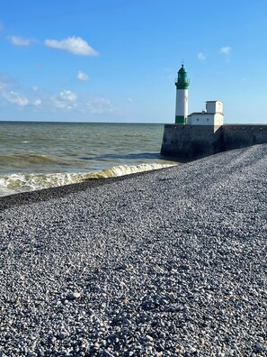 Ein Kiesstrand mit einem Leuchtturm und einer Ufermauer.