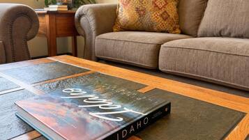 A book titled 'Idaho' on a wooden coffee table in a living room with a sofa and a patterned pillow.