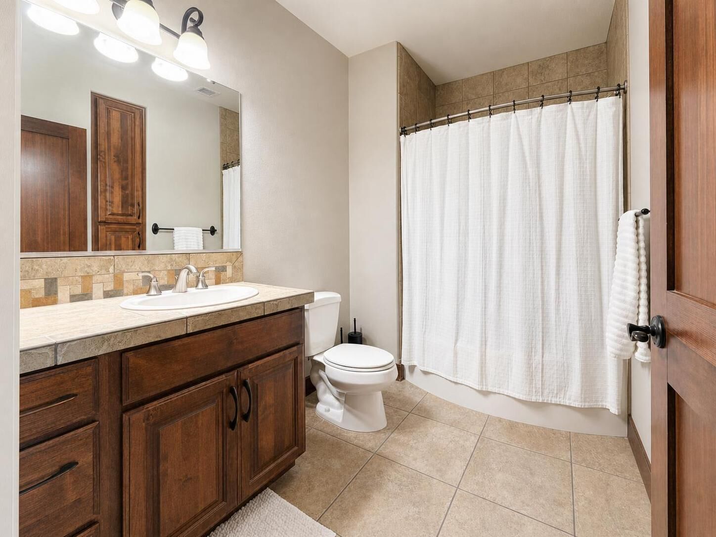 A bathroom with a vanity, sink, mirror, toilet, and shower curtain.