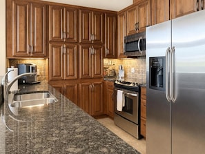 A kitchen with wooden cabinets, stainless steel appliances, a granite countertop, and a built-in oven. - Unwind at Riverstone Loft (Coeur d'Alene)