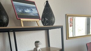 A wooden shelf with various decorative items including a framed picture, a black vase, and potted plants. - Bright, air-conditioned studio with views of the sea and mountains, 5 minutes from the harbor and downtown. (Port-Vendres)