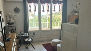 A compact living space with a dining area, a small kitchen, and a balcony with a view. - Bright, air-conditioned studio with views of the sea and mountains, 5 minutes from the harbor and downtown. (Port-Vendres)