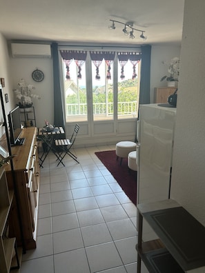Um espaço compacto com área de refeições, uma cozinha pequena e uma varanda com vista.