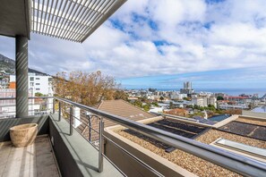 Ein Balkon mit Blick auf eine Skyline und das Meer.