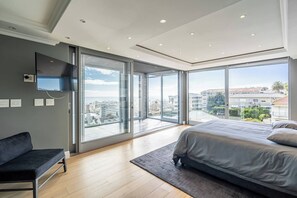 Ein modernes Schlafzimmer mit einem großen Bett, einer Couch und einem an der Wand befestigten Fernseher.