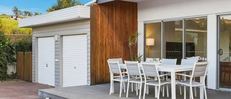 A modern house with a patio, a dining table with chairs, and a garage.