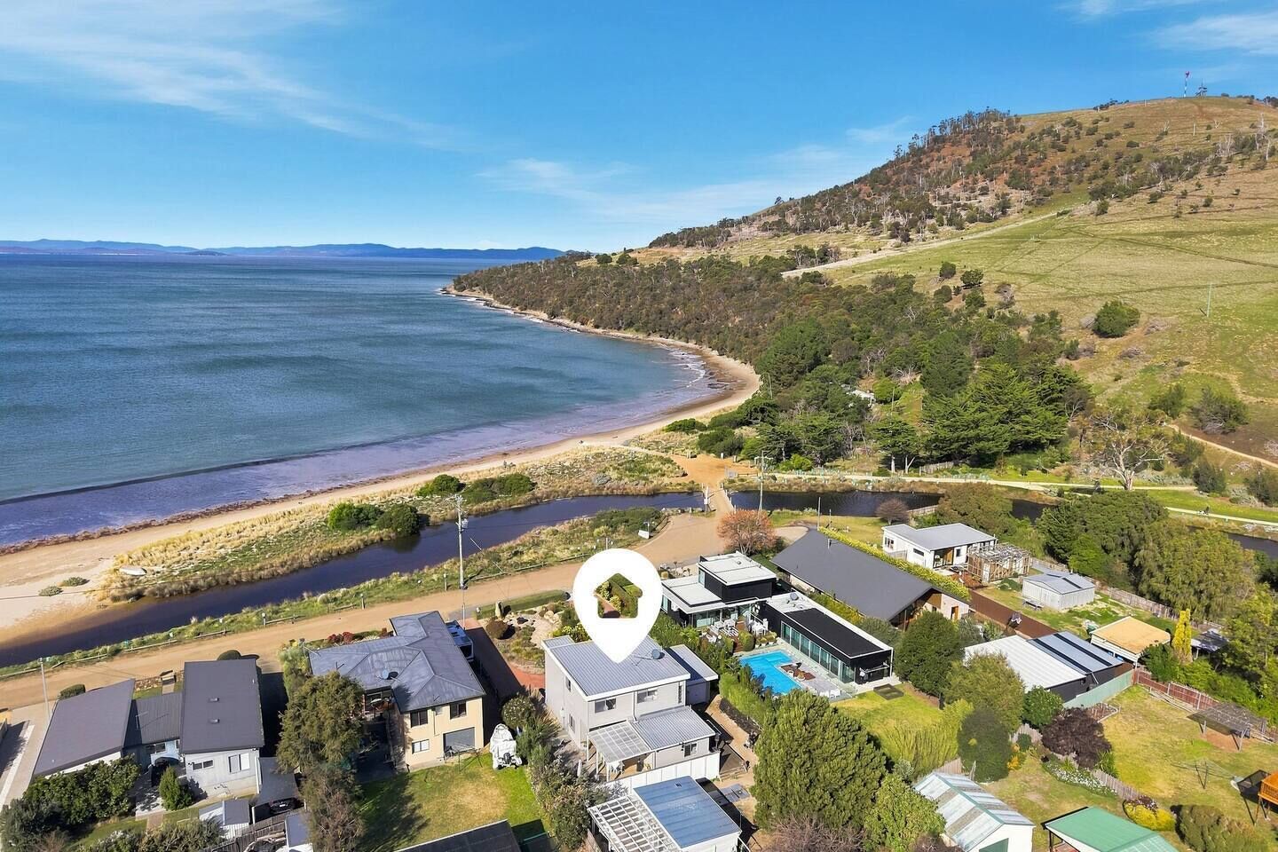 A coastal residential area with houses, a swimming pool, and a beach.