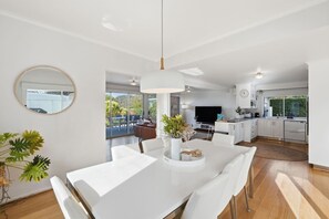 A modern kitchen with white cabinets, a built-in oven, and a large window. - Seven Mile Beach Holiday Home - unwind and restore (Seven Mile Beach)
