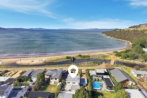 A coastal residential area with houses, a beach, and a large body of water. - Seven Mile Beach Holiday Home - unwind and restore (Seven Mile Beach)