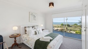 Una camera da letto con un letto, un comodino, una lampada, un quadro incorniciato e vista sull'esterno.