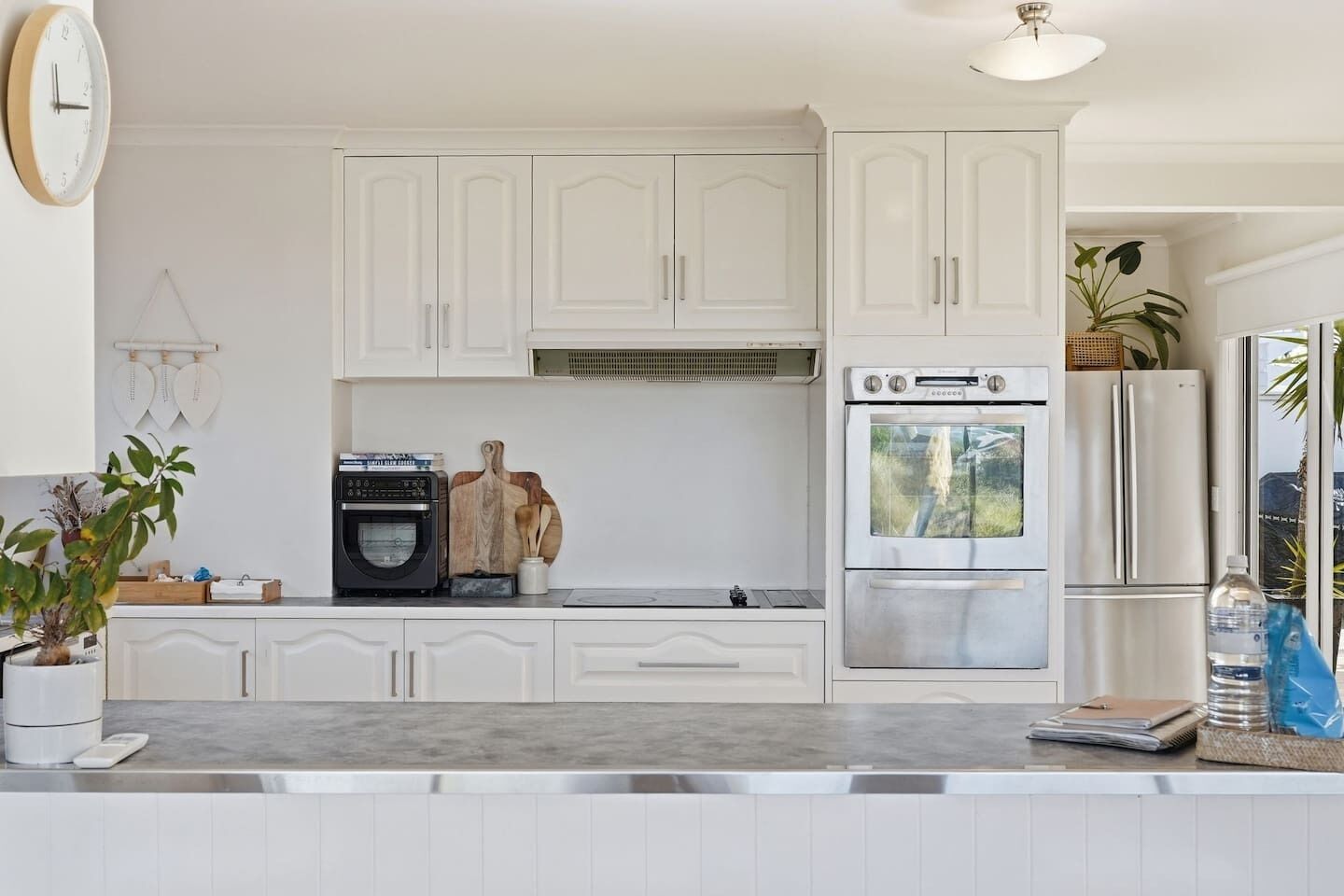 A kitchen with white cabinets, a built-in oven, a refrigerator, and a coffee maker.