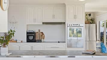 A kitchen with white cabinets, a built-in oven, a refrigerator, and a coffee maker.