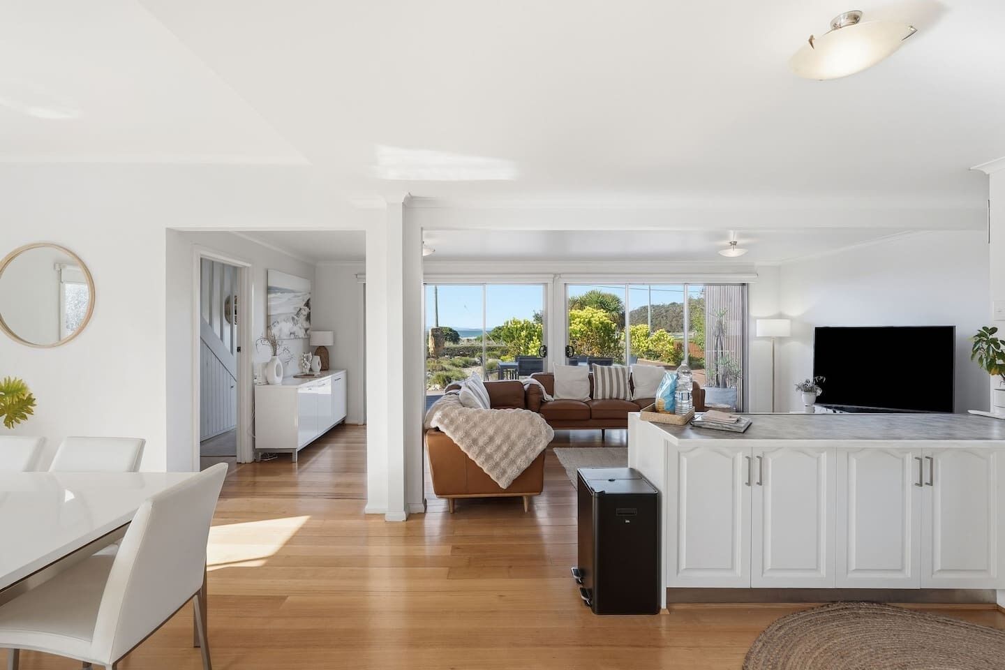 A modern living space with a dining area, kitchen, and a balcony with a view.