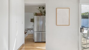 Una cucina moderna con un frigorifero in acciaio inossidabile, un pavimento in legno e un quadro appeso al muro.