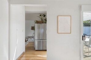 Eine moderne Küche mit einem Edelstahl-Kühlschrank, Holzboden und einem gerahmten Kunstwerk an der Wand.