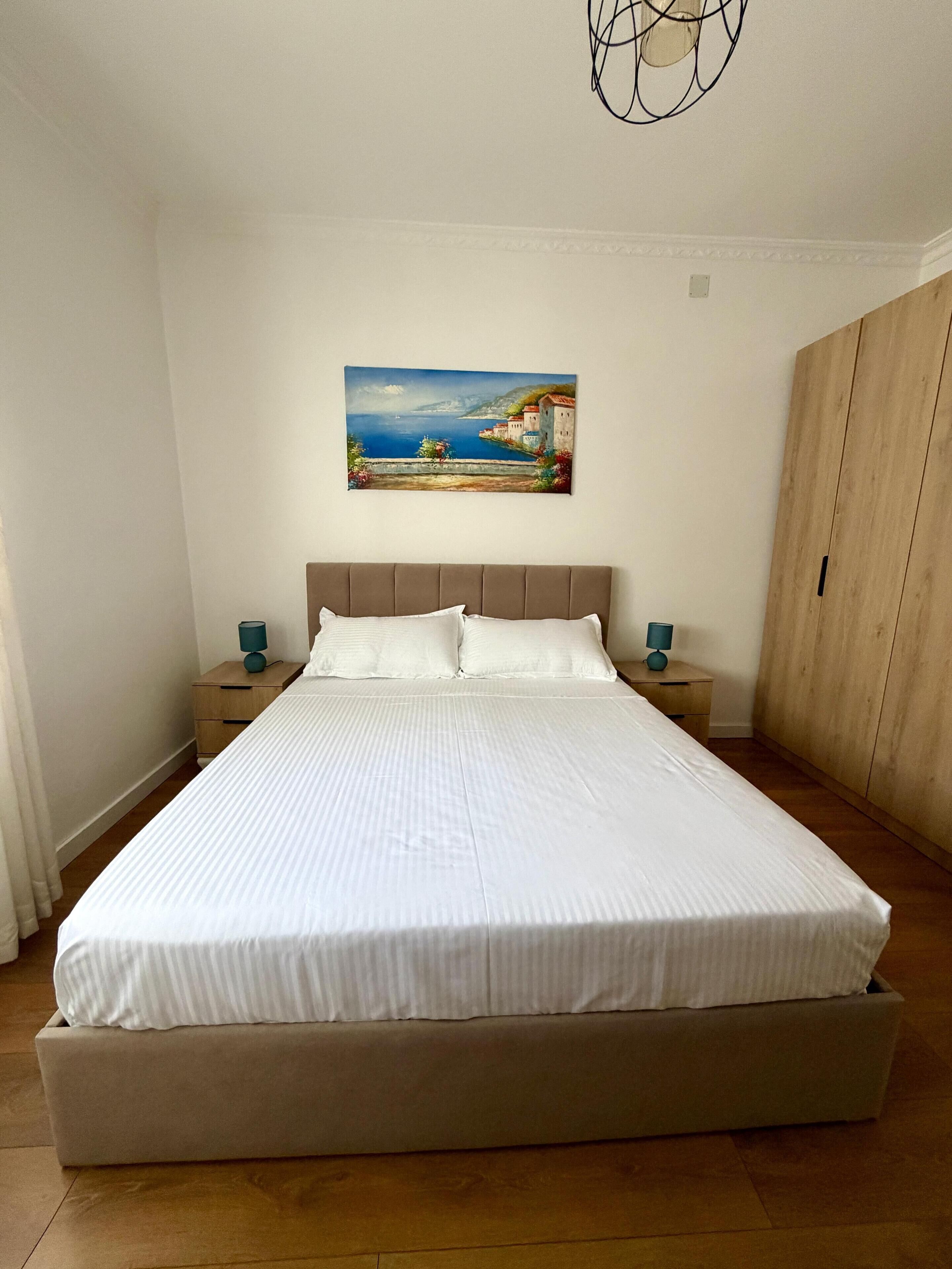 Una camera da letto con un letto grande, un armadio in legno e un quadro appeso al muro.