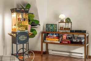 A vintage popcorn machine with a bicycle wheel base, a bookshelf with board games, and a lamp on a side table. - Sky Lodge -Hot Tub, A-Frame, Star Net, Epic Views, Fire Pit, Movie Room, Jacuzzi (Fairplay)