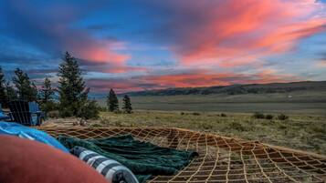 A campsite with a view of a sunset over a hilly landscape.