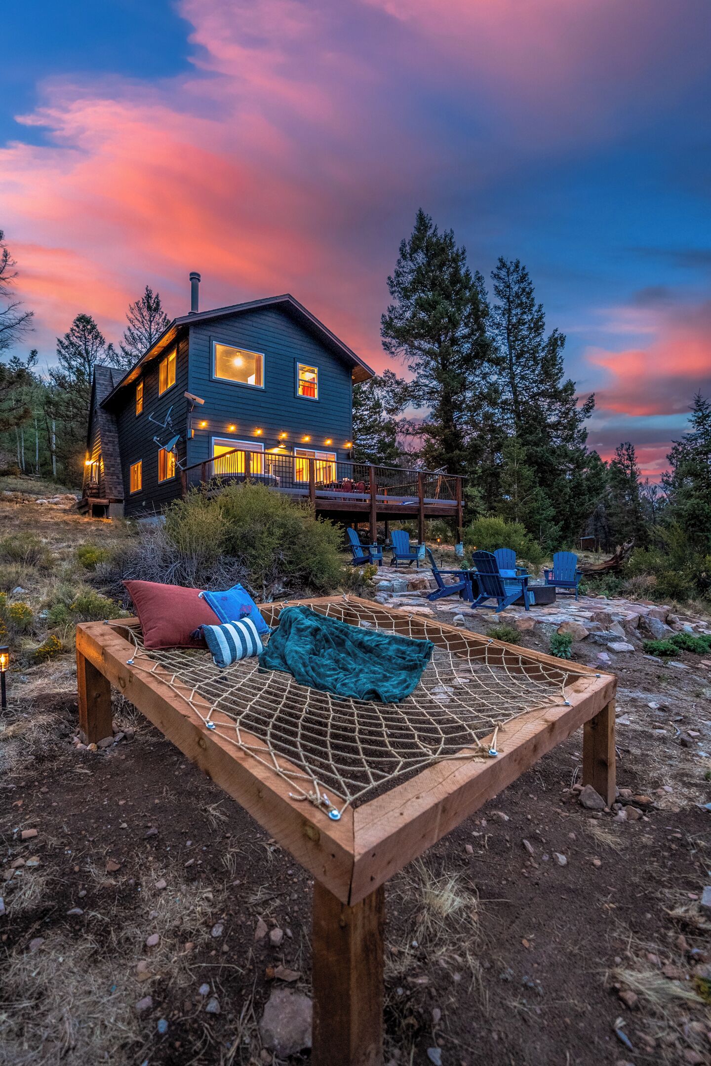A cabin with a deck, outdoor seating, and a hammock.