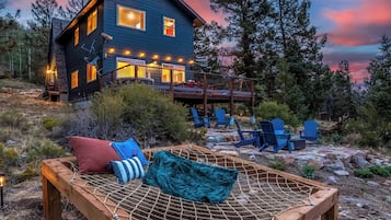 A cabin with a deck, outdoor seating, and a hammock.
