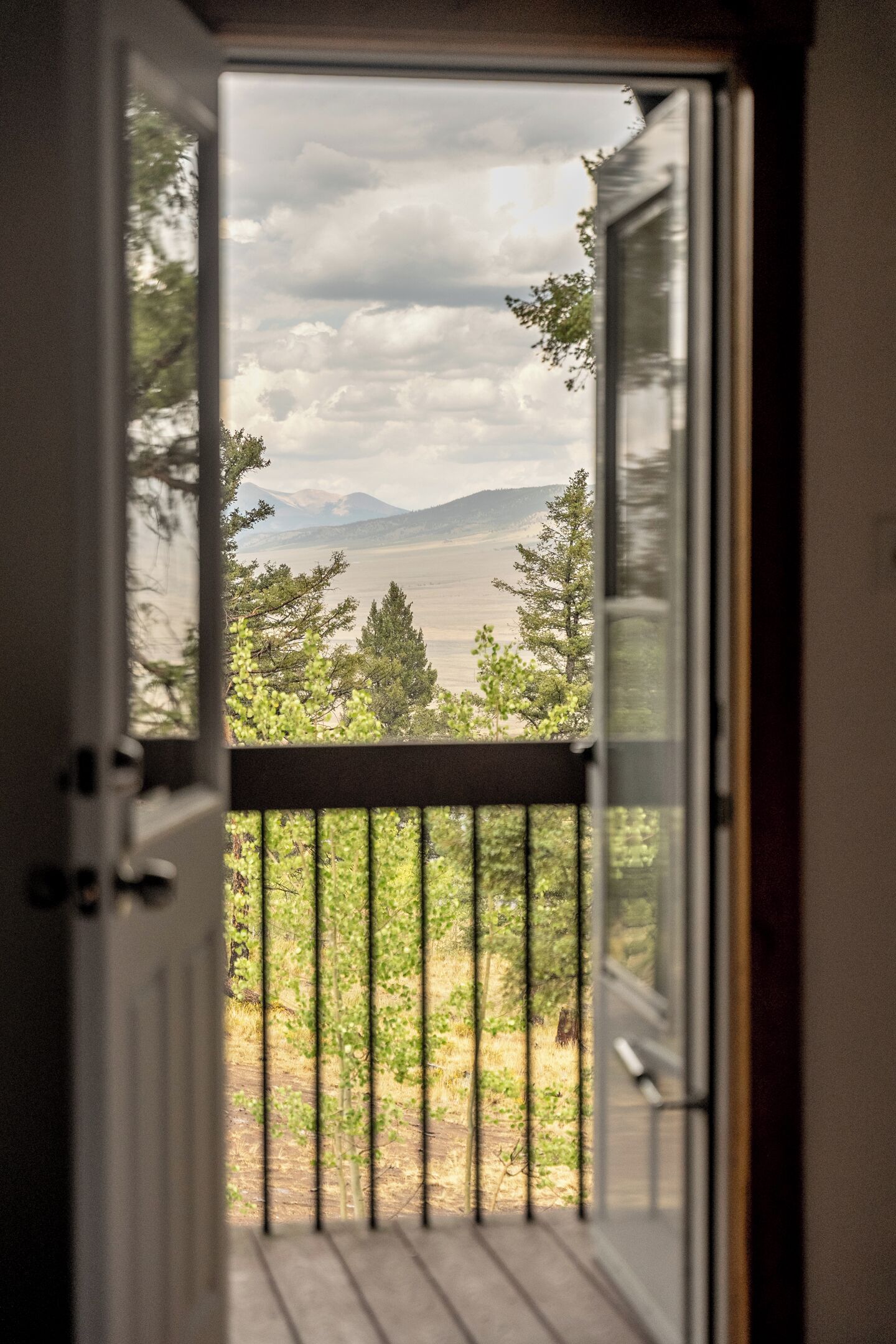 A door leading to a balcony with a view of a mountainous landscape.