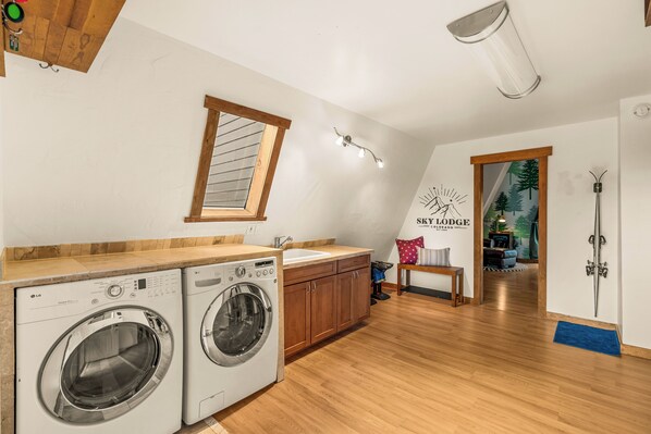 Ein Waschbereich mit zwei Waschmaschinen, einer Holz Arbeitsplatte, einem Fenster und einer Wandleuchte.