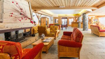 A spacious lobby with wooden furniture, a fireplace, and a stone pillar.