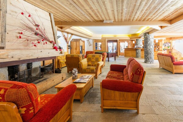 A spacious lobby with wooden furniture, a fireplace, and a stone pillar.