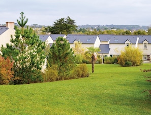 A row of houses with a well-maintained lawn and trees in the foreground.