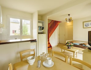 A kitchen with a dining area, a refrigerator, a microwave, and a staircase.