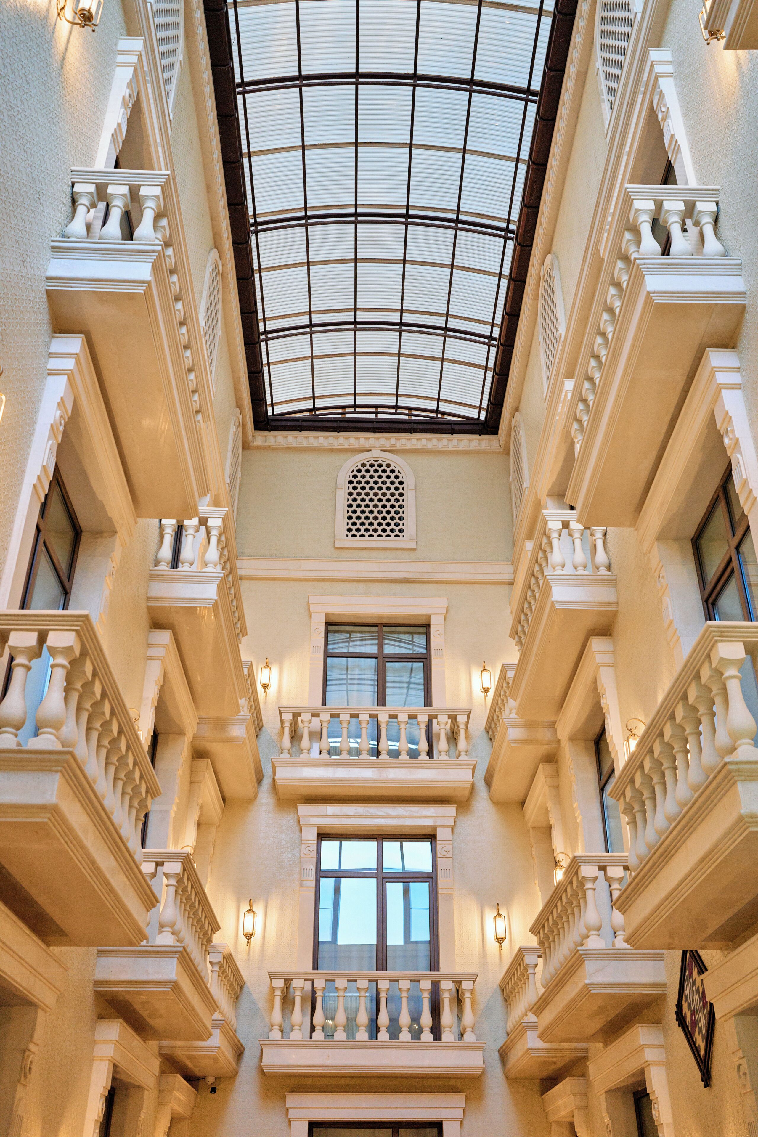 A grand atrium with a glass ceiling, ornate balconies, and classical architectural details.