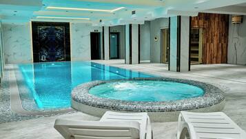 Une piscine intérieure moderne dotée d’un jacuzzi, de chaises longues et d’un mur en bois.