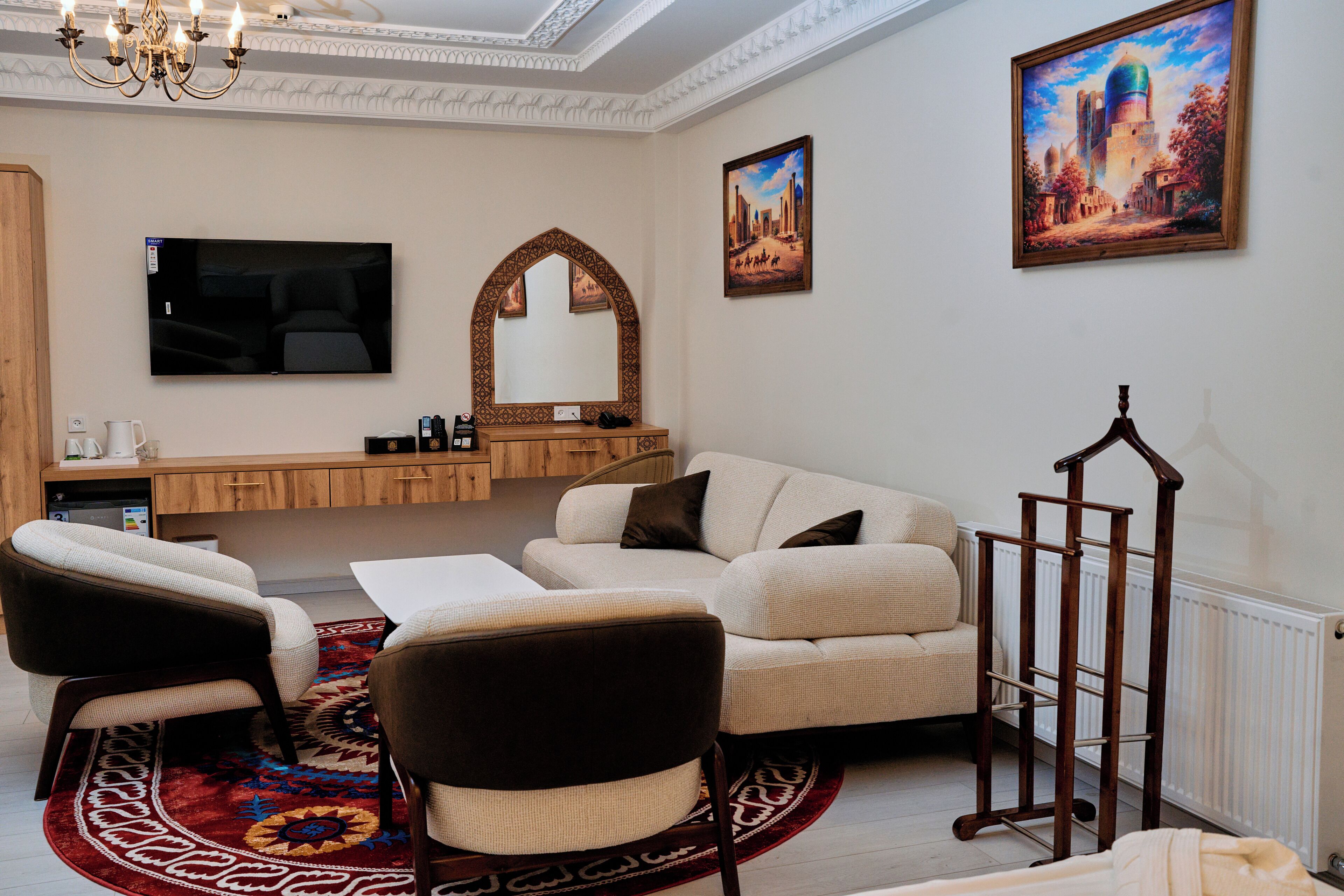 A living room with a sofa, chairs, a TV, a fireplace, and a large painting on the wall.
