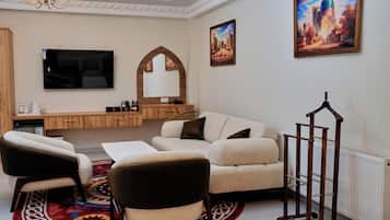 Una sala de estar con un sofá, sillas, televisor, chimenea y un cuadro grande en la pared.