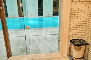 Un área acristalada con piscina, pared de ladrillo y banco de madera.