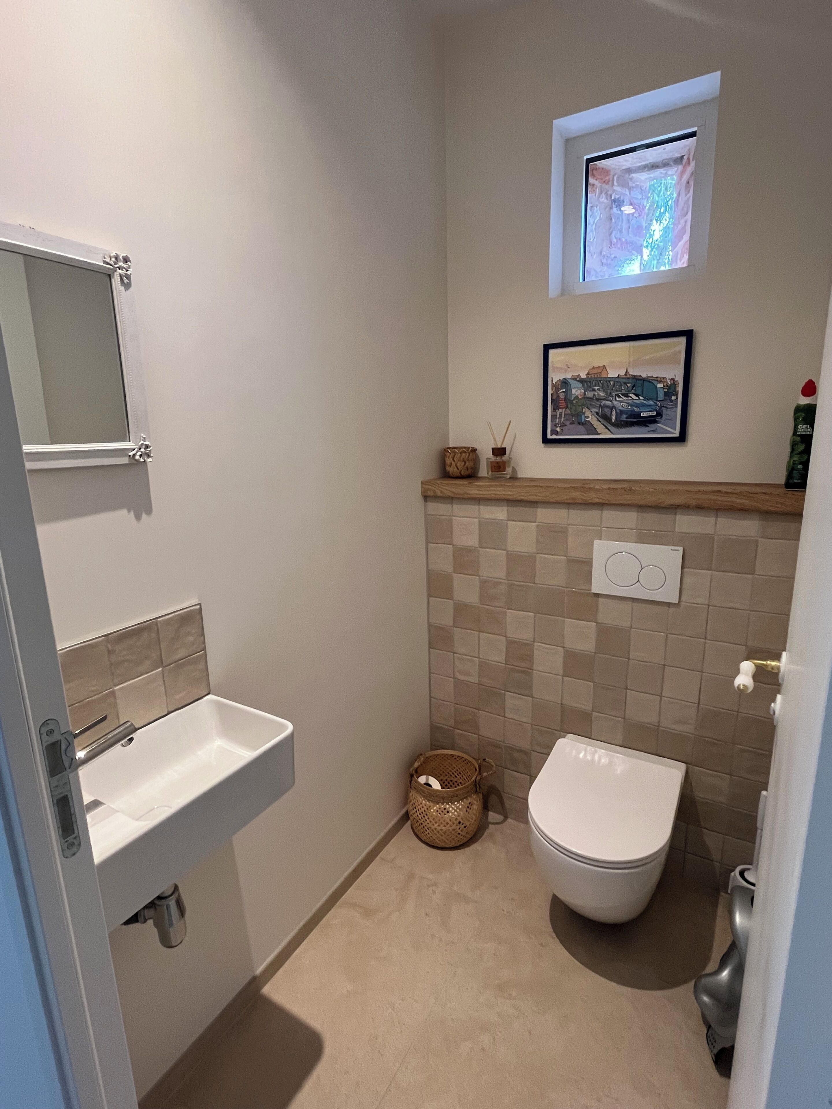 Un baño con lavamanos, inodoro y un ventanal pequeño.