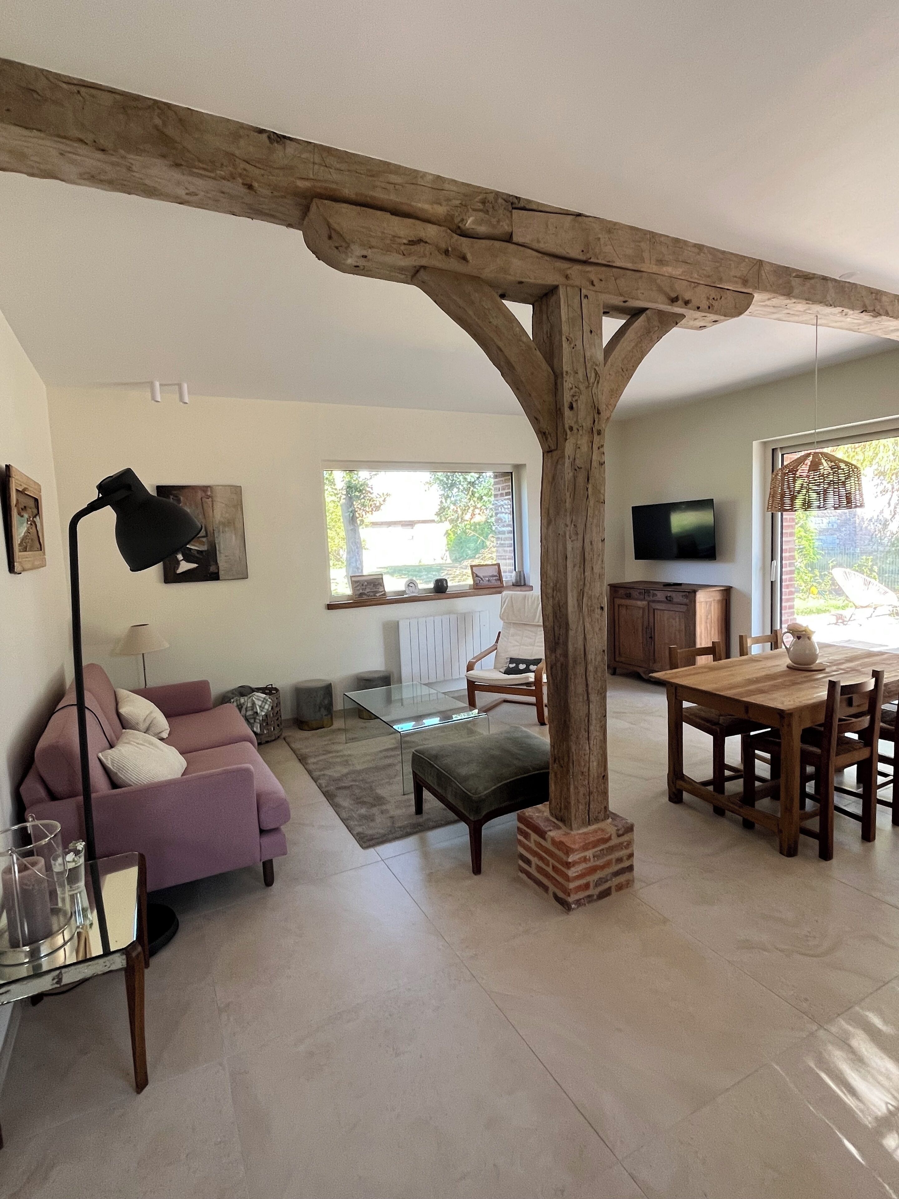 Un salon comprenant un canapé, une table basse en verre, une table à manger en bois et un téléviseur.
